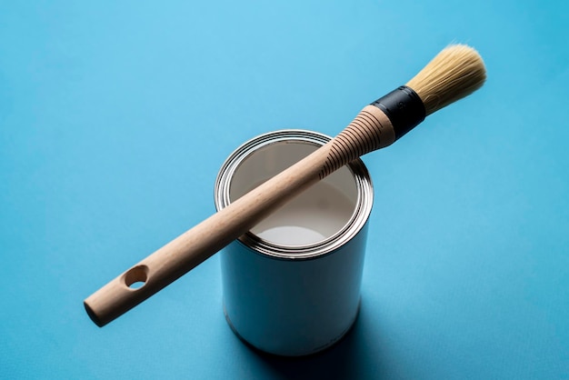 A paint brush on top of can with paint on the colored surface creative art concept