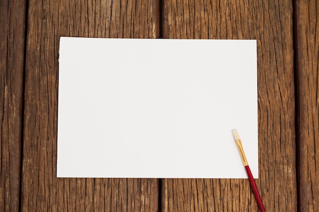 Paint brush and white paper on wooden table