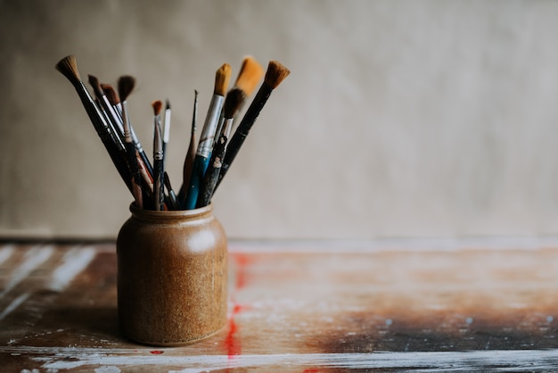 Paint brushes in a ceramic jar.