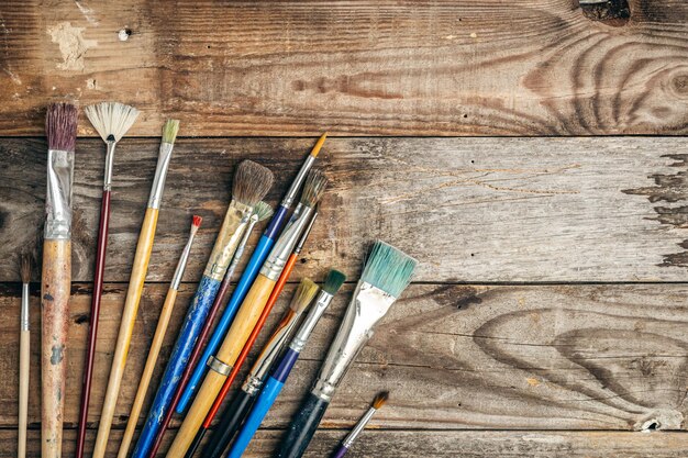 Paint brushes of different sizes on a wooden background flat lay