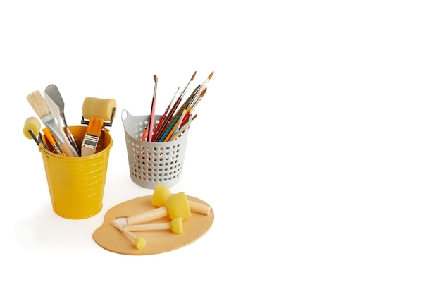 Photo paint brushes rollers and spatulas in buckets and round sponge foam brush on a wooden pallette