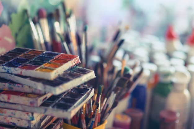 Paint brushes and watercolor paints on the table in a workshop