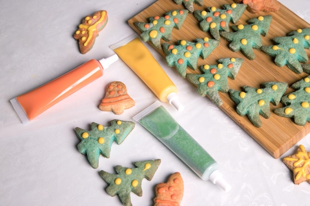 Paint and finished painted Christmas gingerbread cookies on the white background of the tablecloth