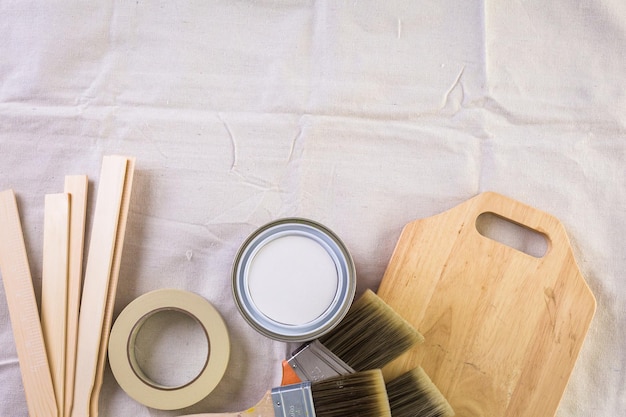 Paint in metal paint can and painters tools on a canvas drop cloth.