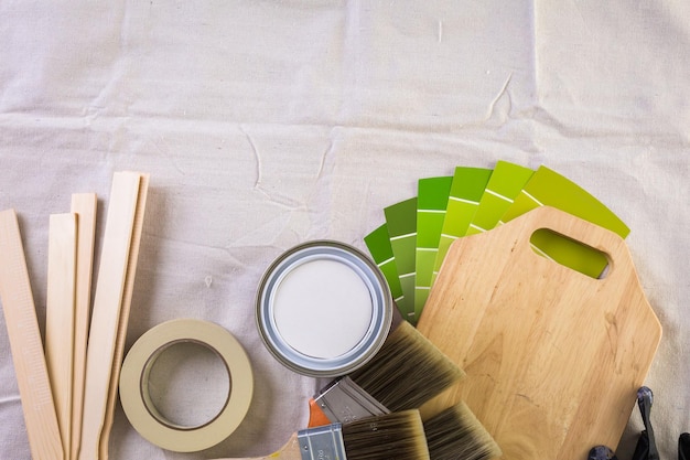 Paint in metal paint can and painters tools on a canvas drop cloth.