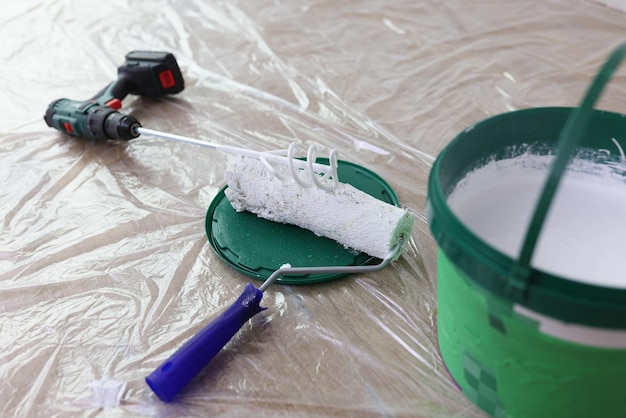 Paint mixer with white paint bucket and roller brush on floor home improvement painting and