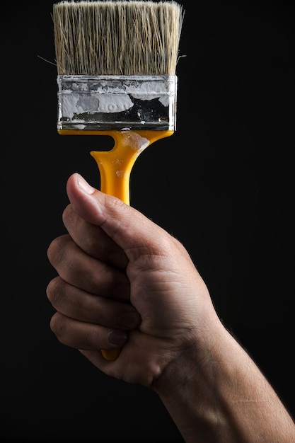 Paint and repair brush in hand on a black background