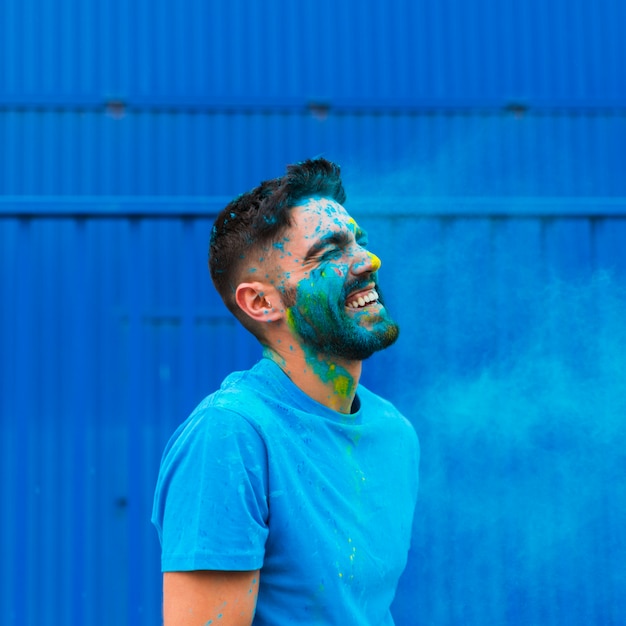 Paint stained young man laughing on Holi festival