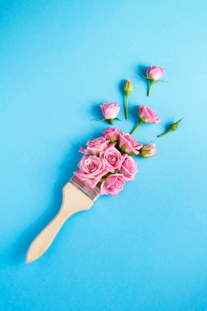 Paintbrush with pink roses on the blue background Top view Location vertical