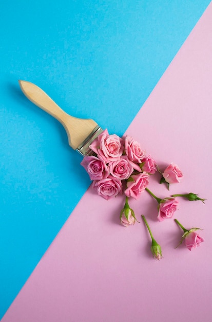 Paintbrush with pink roses on the colored background Top view Closeup Location vertical