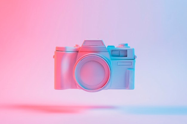 Painted camera floating with shadow against pink backdrop