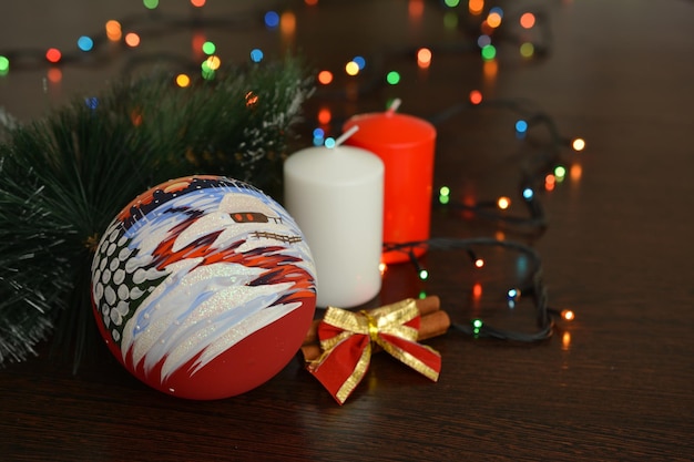 painted christmas sphere on the table with red and white candles, close-up