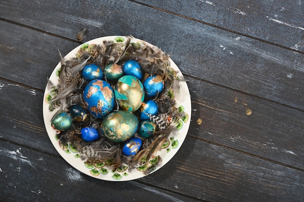 Painted colored Easter eggs on animal skin in plate on dark wooden background Boho stile