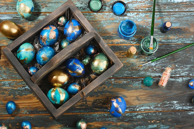 Painted colored Easter eggs in dark wooden box on dark wooden background Boho stile