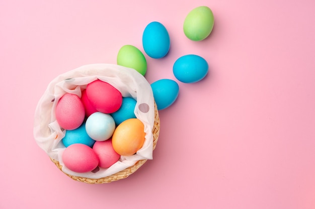 Painted Easter eggs in decorative nest on pink surface