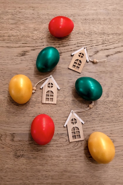 Painted easter eggs red green and gold colours with three toy houses, property sale concept, top view