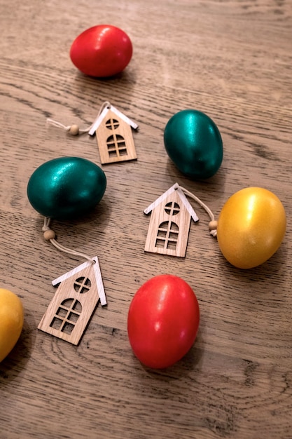 Painted easter eggs red green and gold colours with three toy houses, property sale concept, top view