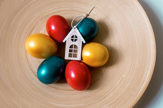 Painted easter eggs red green and gold colours with three toy houses, property sale concept, top view