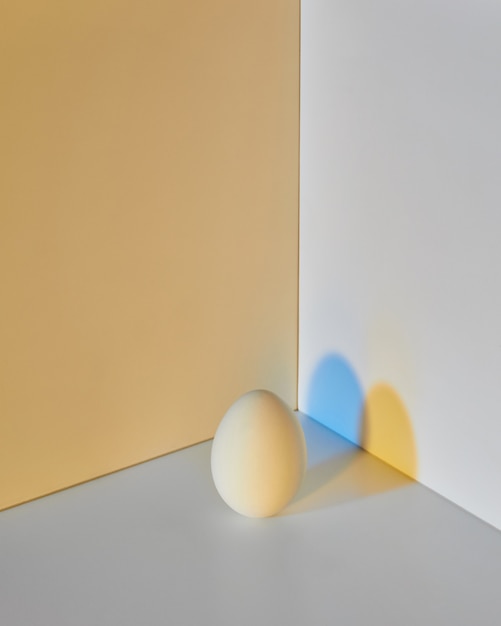 Painted egg on a grayyellow double background with a reflection of blueyellow shadows and copy space