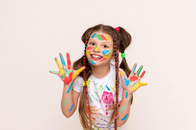 Painted hands and face Portrait of a girl child stained in multicolored paint Children's artistic creativity Isolated white background