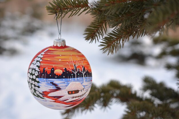 painted sphere hanging on the branch of fir tree, close-up