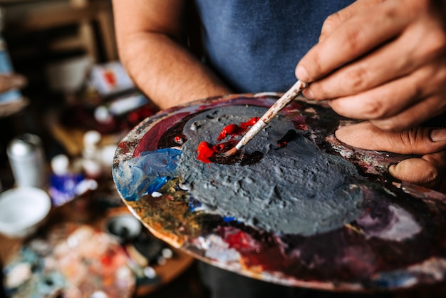 Painter holding palette and paintbrush. Close-up.