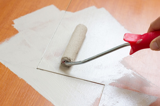 Painter with paint roller painting a wooden commode