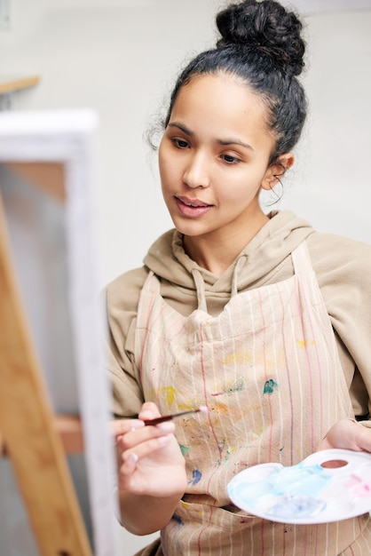 Painting brings her peace. Low angle shot of an attractive young woman painting on a canvas in her studio.