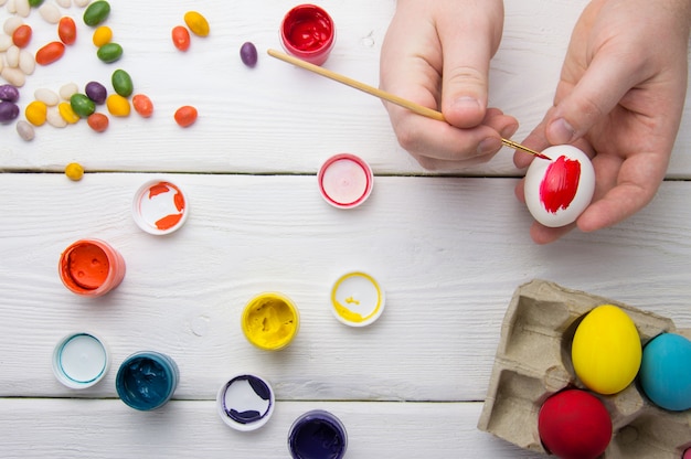 Painting easter eggs on wooden table with paint and candy