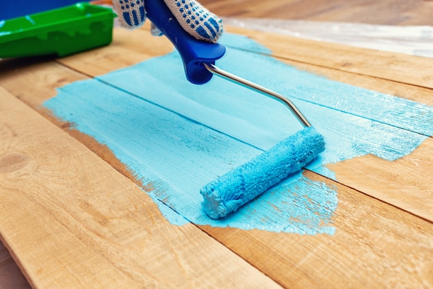 Painting with the paint roller on the blue wooden DIY 