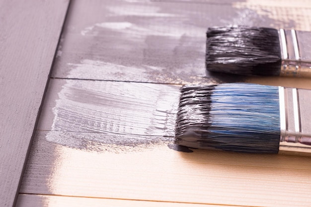 Painting a wooden surface with a brush and grayxA paint Natural wooden texture Renovation or repair construction