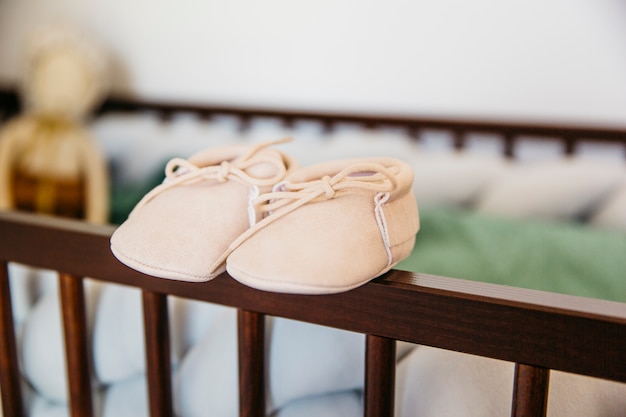 Pair of baby shoes on the edge of wooden crib