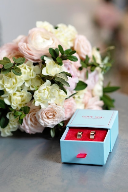 A pair of beautiful wedding rings and a delicate bridal bouquet of roses Wedding ceremony Soft selective focus