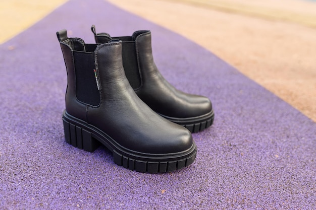 A pair of black leather boots on a purple mat