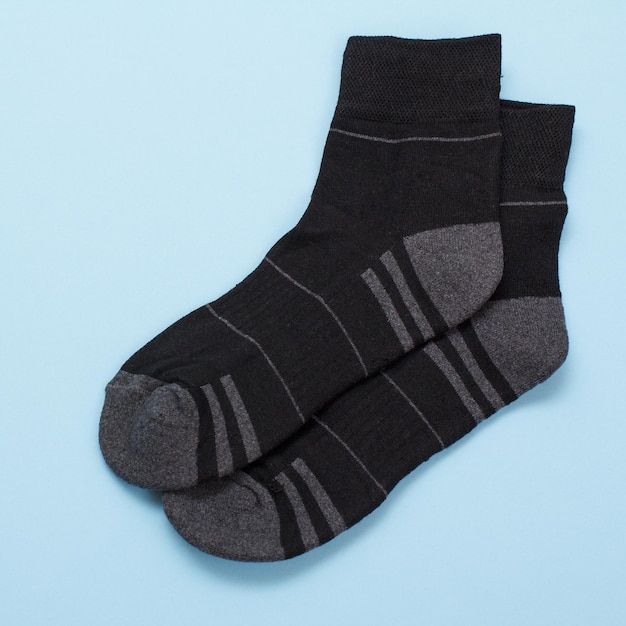 Pair of black warm woolen men socks on a blue background, Top view with copy space.