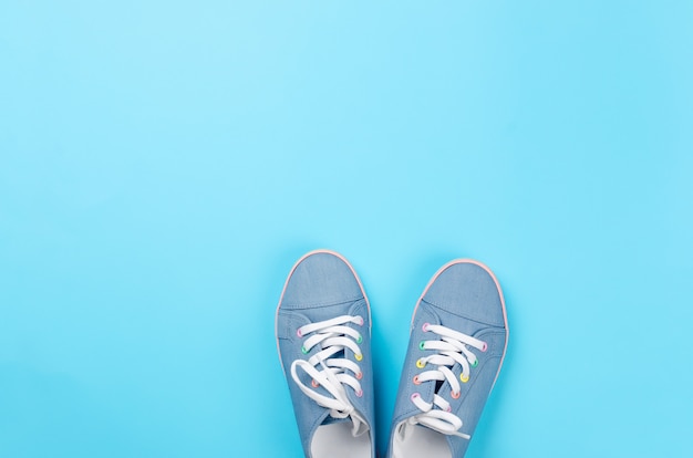 A pair of blue canvas sneakers on light blue background