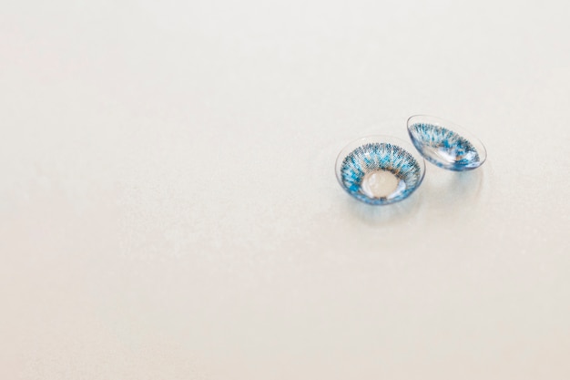 Pair of blue contact lenses on gray  background