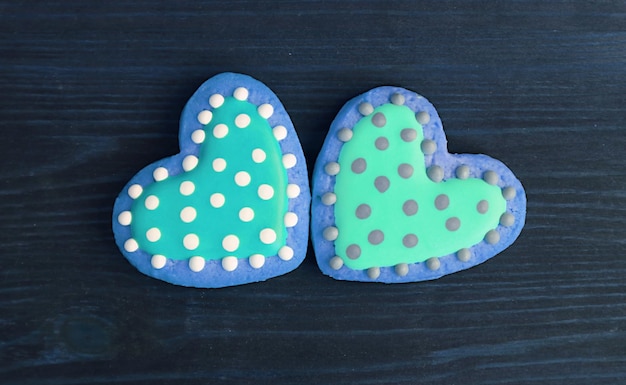 Pair of blue dotted heart shaped royal icing cookies on navy wooden background