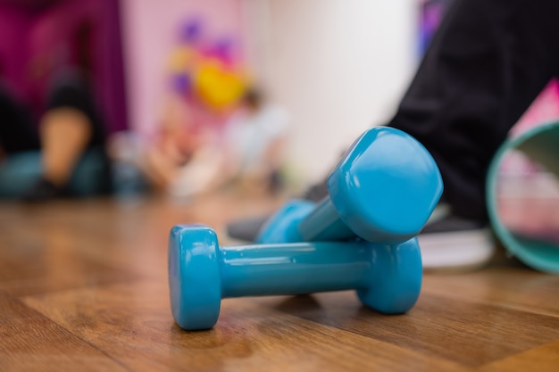 Photo a pair of blue hard plastic hex dumbbells lying on the rubber matted floor of a gym or health club.