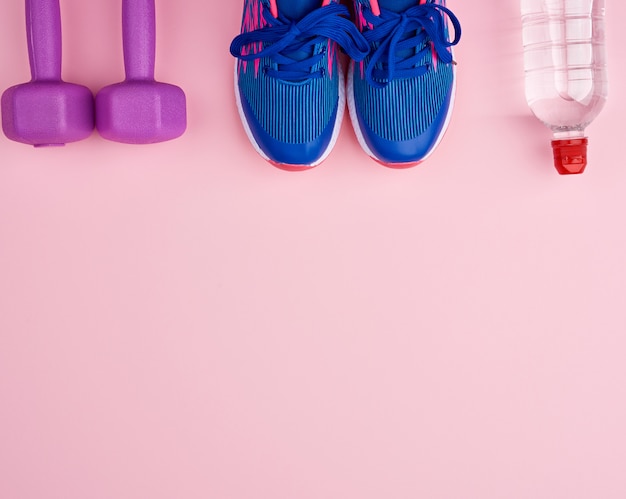 pair of blue sneakers, plastic dumbbells and bottle of water