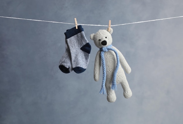 Pair of child's socks and toy bear hanging on laundry line against dark background