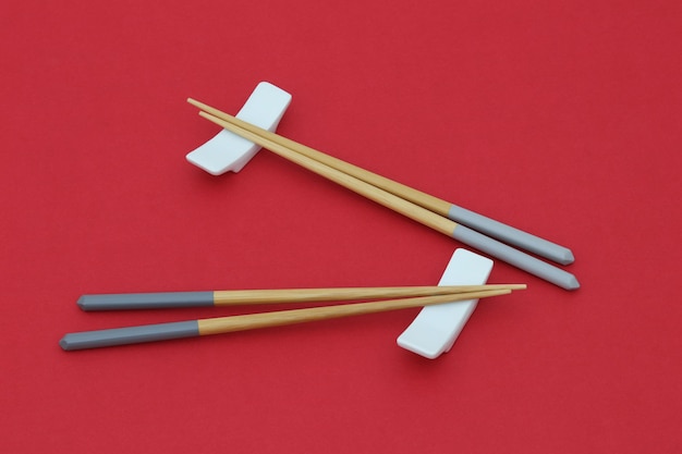 A pair of chopsticks sit on top of a red background.