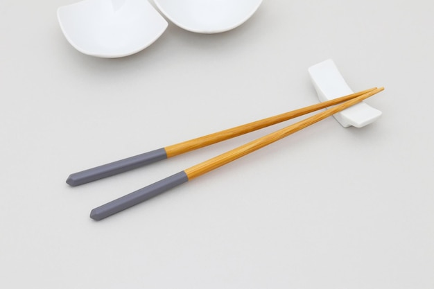 A pair of chopsticks with a yellow and gray handle, the other two are on a white table.