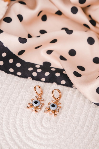 A pair of evil eye earrings are on a bed.