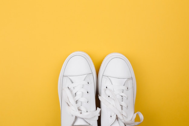 Pair of fashionable sneakers on yellow table.