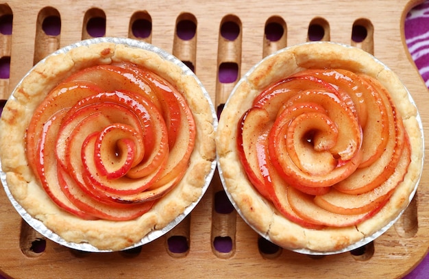 Pair of Fresh Baked Homemade Rose Shaped Apple Tartlets on Wooden Breadboard