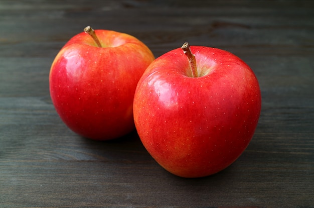 Pair of fresh ripe red apple isolated on dark colored wooden surface