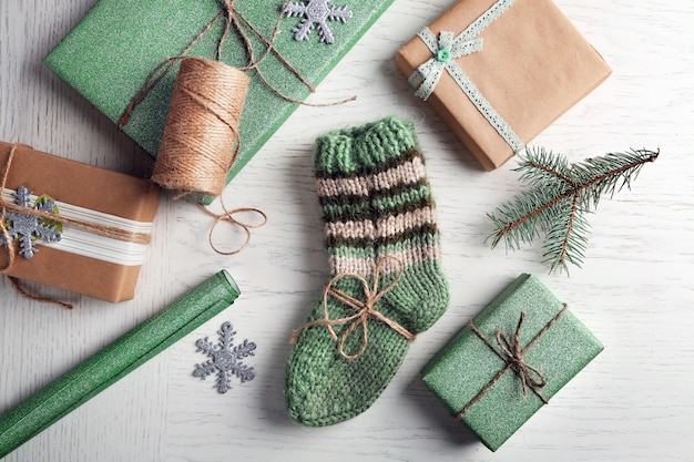 Pair of knitted socks with wrapped gifts for Christmas on light table