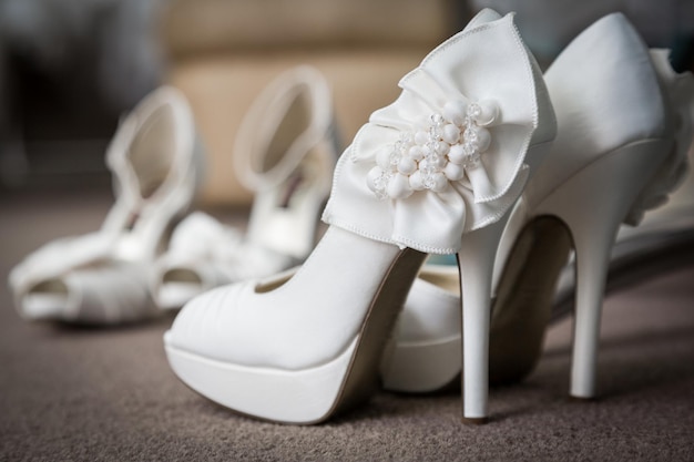 Pair of new elegant white wedding shoes standing on a floor in a wedding studio