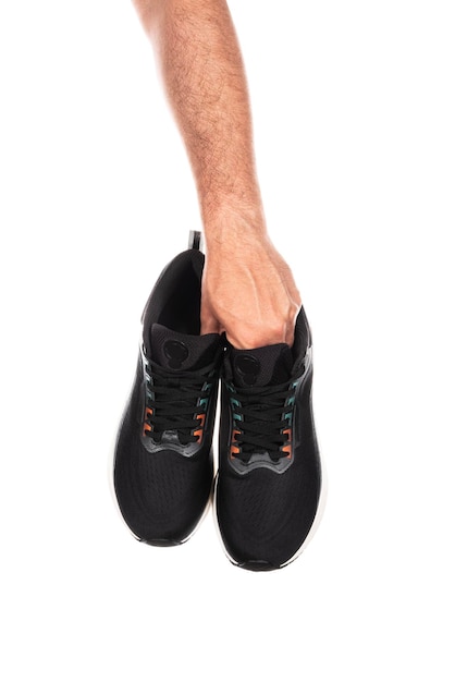 Pair of new unbranded black sport running shoes or sneakers in male hand isolated on white background with clipping path